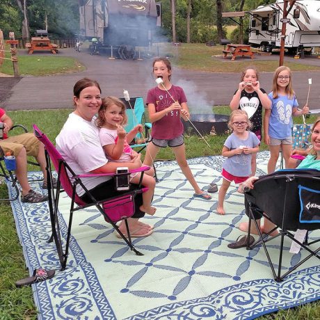 happy family in camping chairs with fire pit